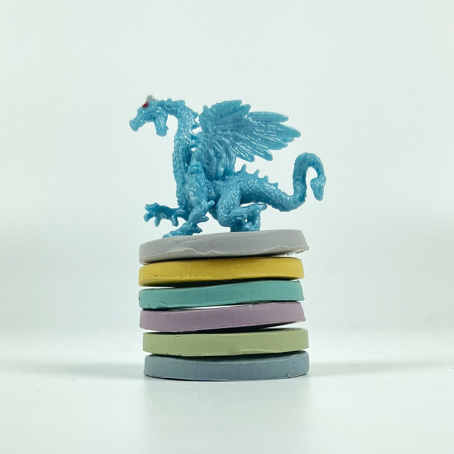 Stacked discs of each polymer clay color in this palette with a fierce baby blue dragon