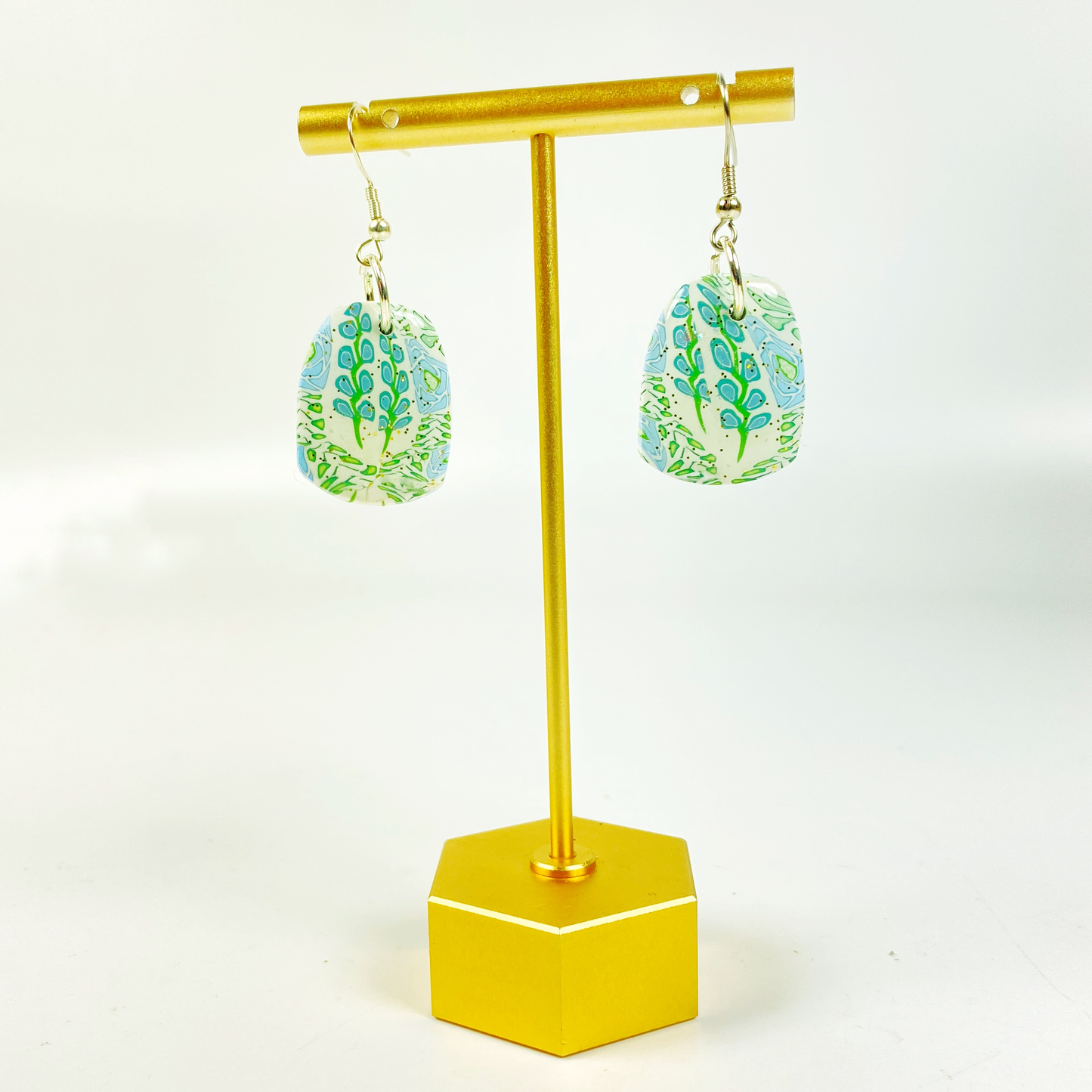 Blue Blossom Handmade Polymer Clay Dangle Earrings hanging from a brass earring stand
