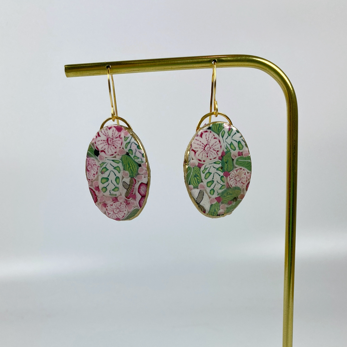 Pink Woodland Handmade Polymer Clay Oval Dangle Earrings on a brass earring display stand