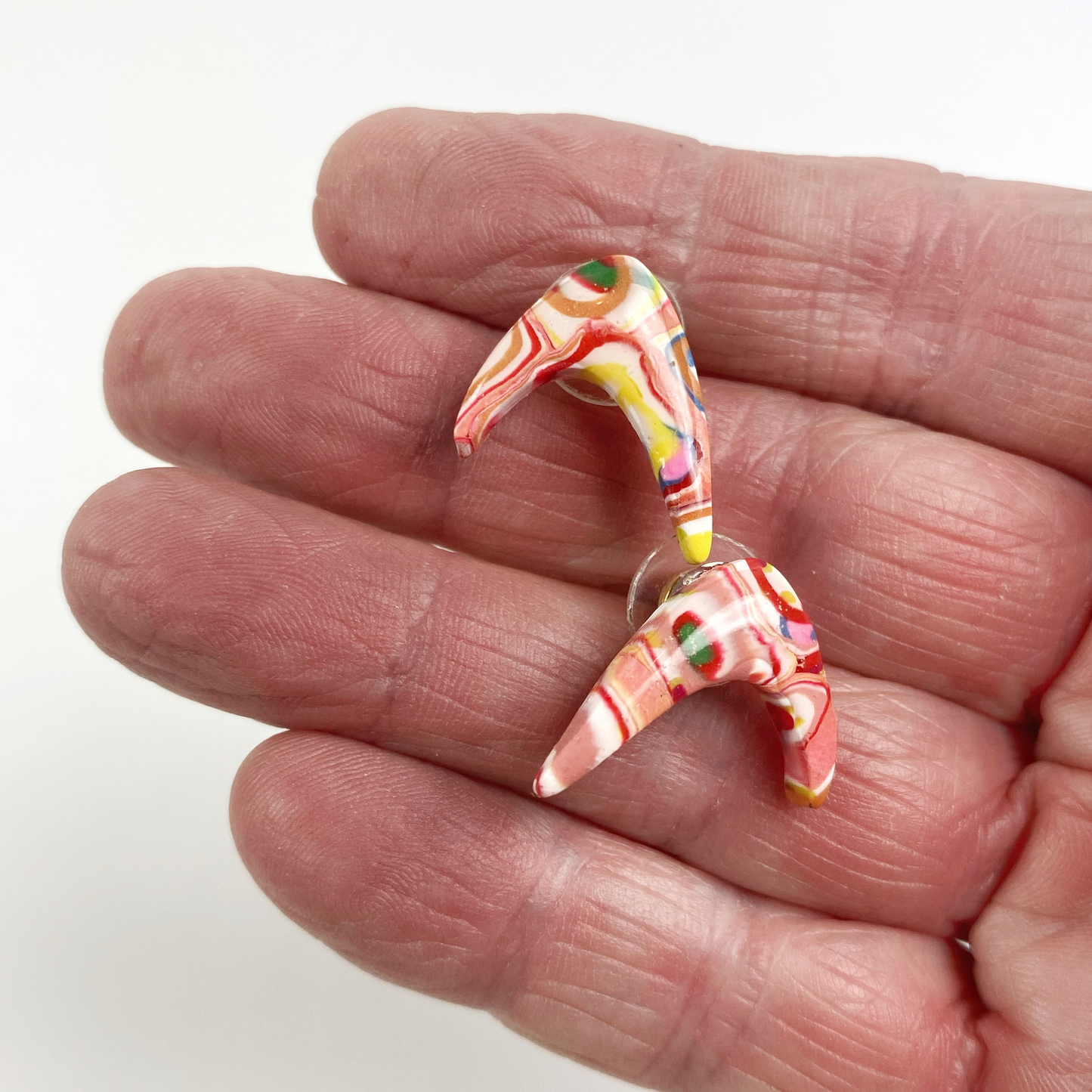 Pink Boomerang Stud Earrings handheld for size reference.
