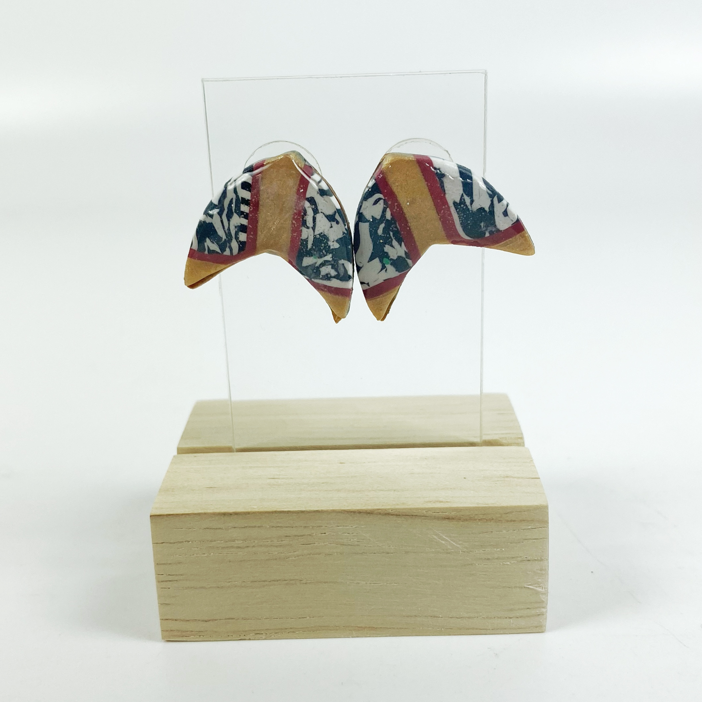 Red and Gold Handmade Polymer Clay Boomerang Stud Earrings on an Acrylic earring display.
