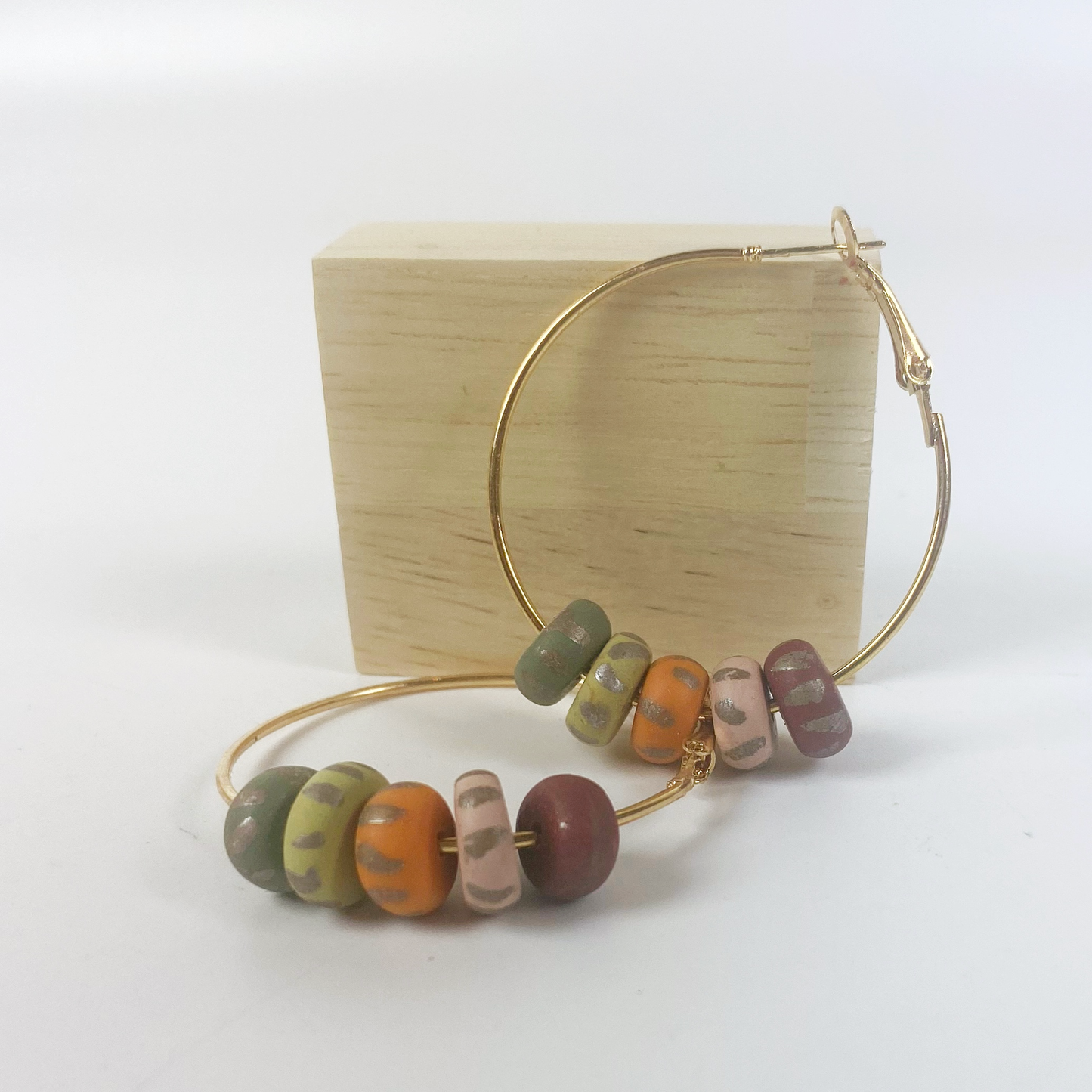 Handmade Polymer Clay Hoop Earrings with Autumn Beads displayed with a blond wood block
