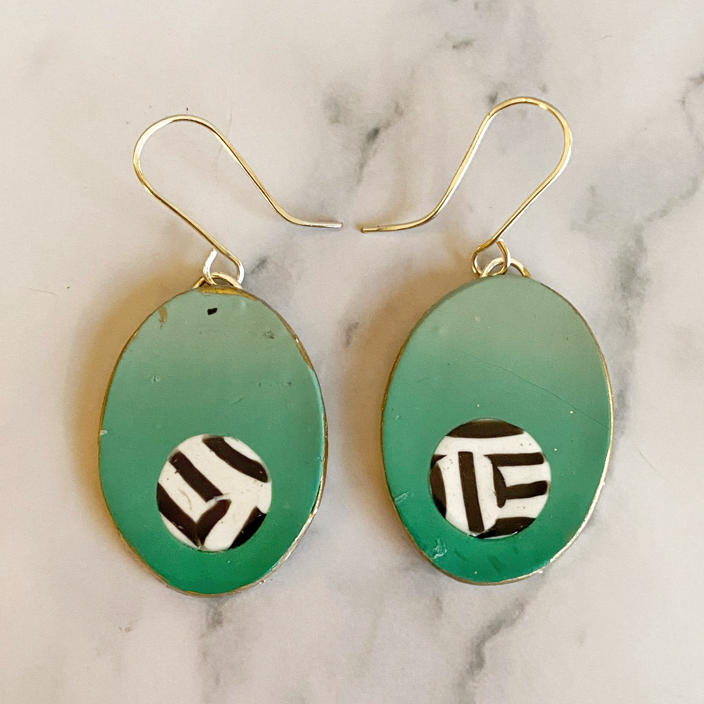 Green earrings with black and white pattern on a marble background