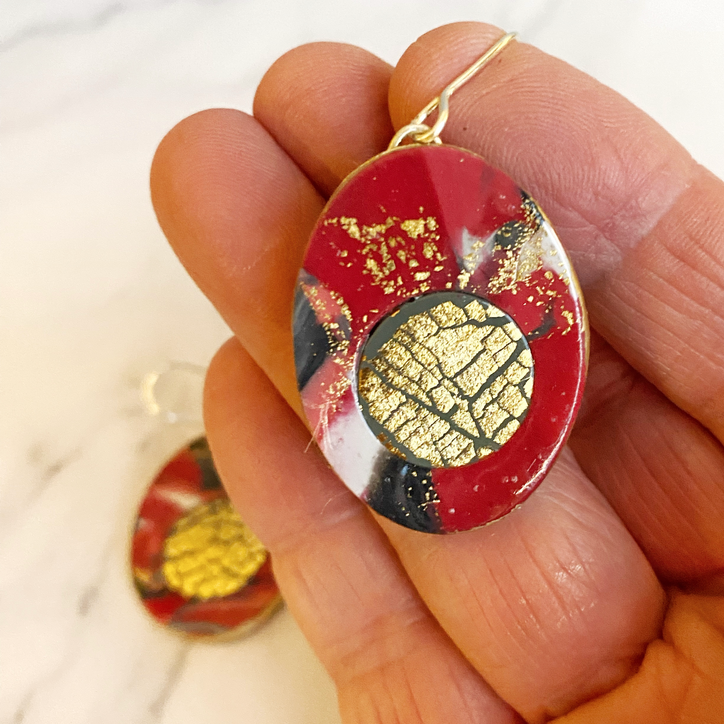 Red Marbled Polymer Clay Earrings with Gold Inset handheld for size reference