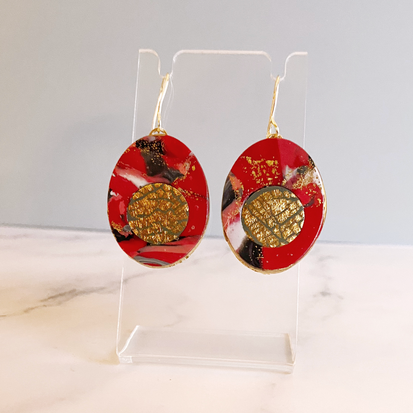 Red Marbled Polymer Clay Earrings with Gold Inset on an acrylic display stand.