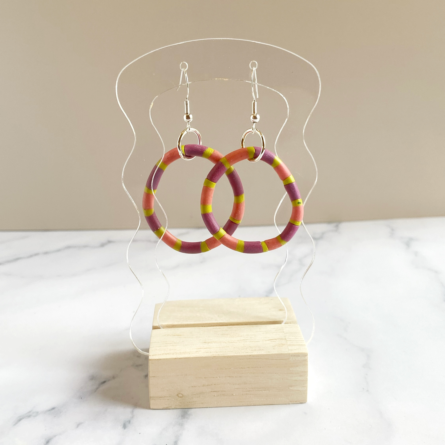 Polymer Clay Rhythm Hoops in Pink, Lavender and Citron displayed on an acrylic stand.
