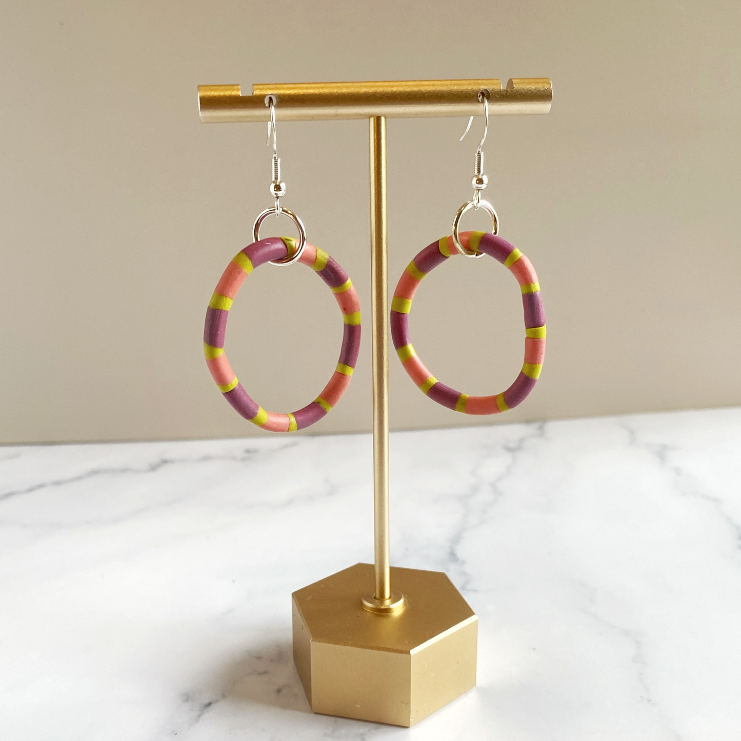 Polymer Clay Rhythm Hoops in Pink, Lavender and Citron on a brass earring stand.