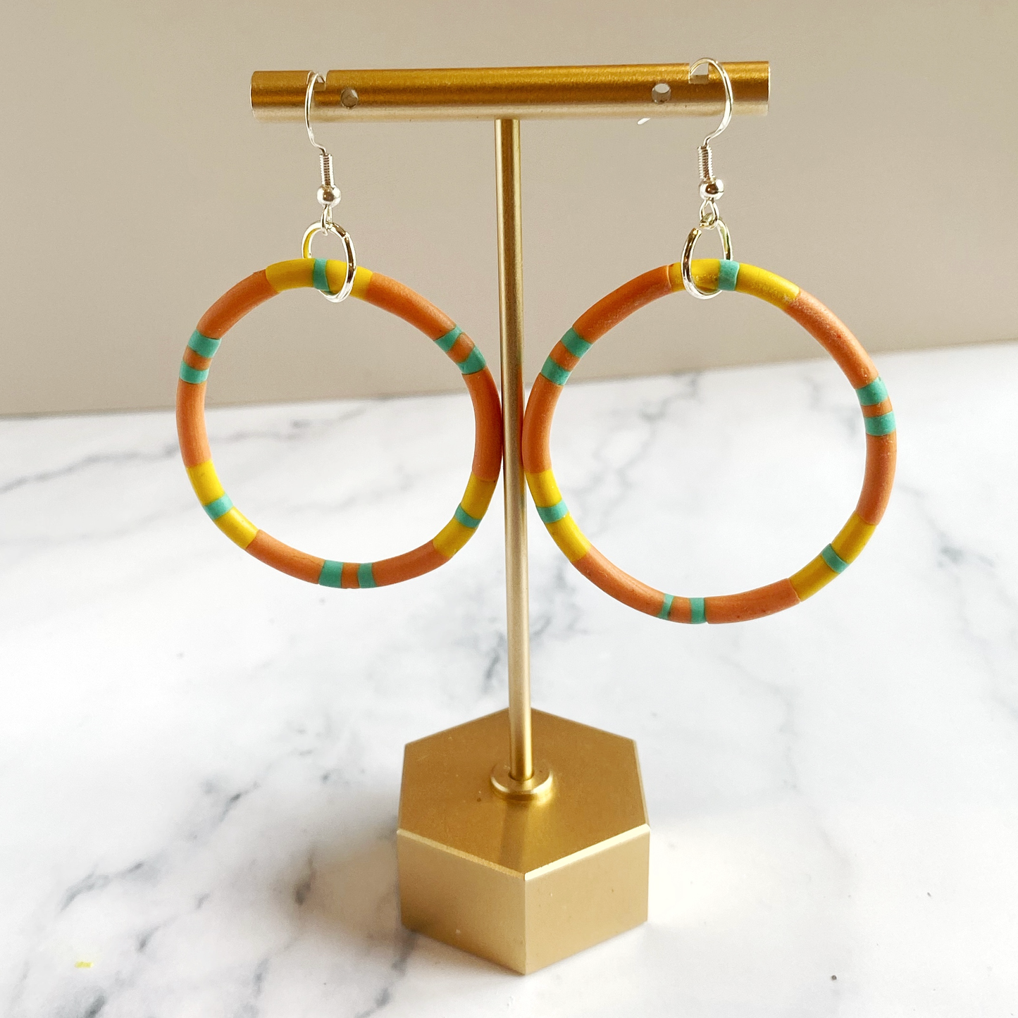 Colorful hoop earrings on a gold stand with a marble background