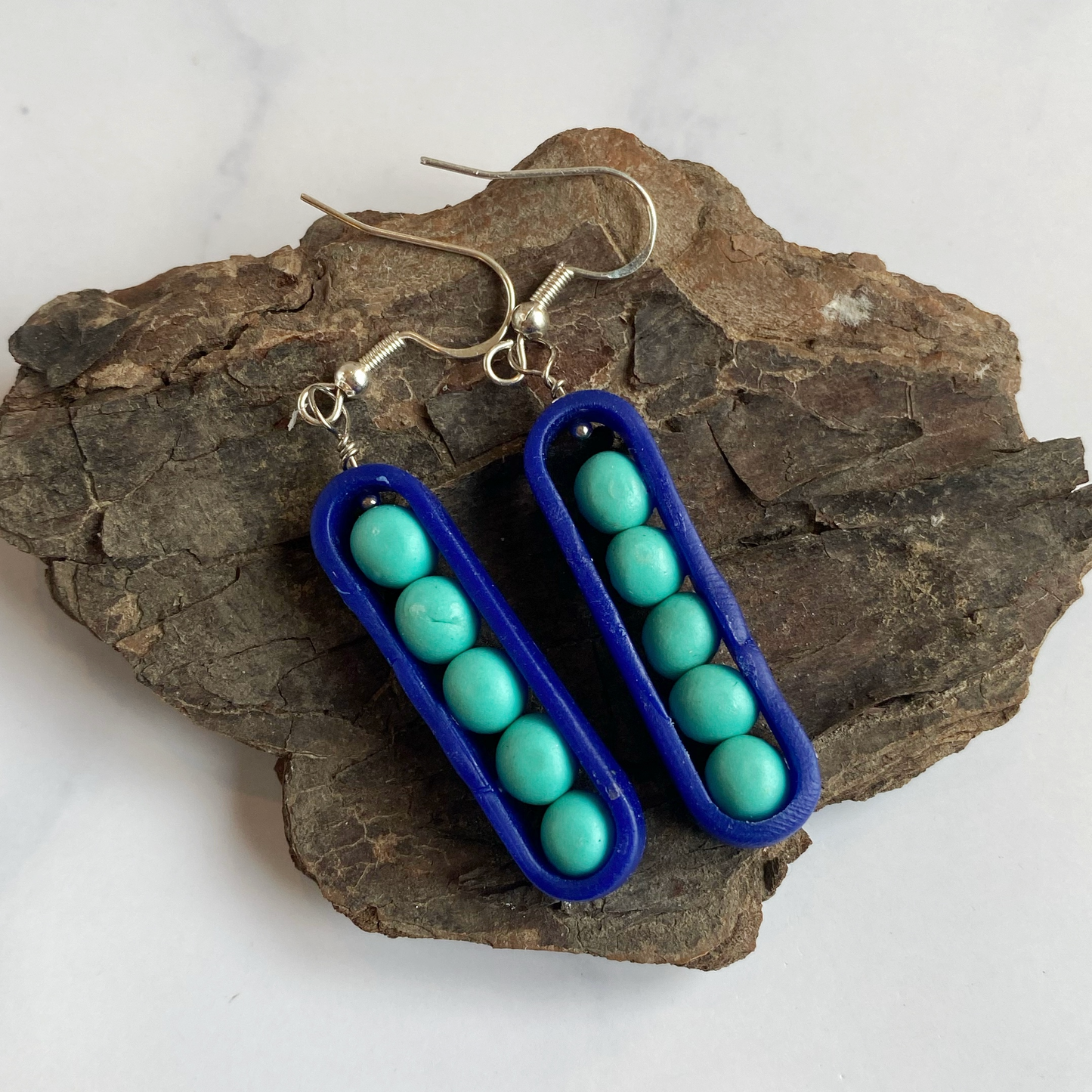 Earrings with blue frame and turquoise beads on a piece of wood.