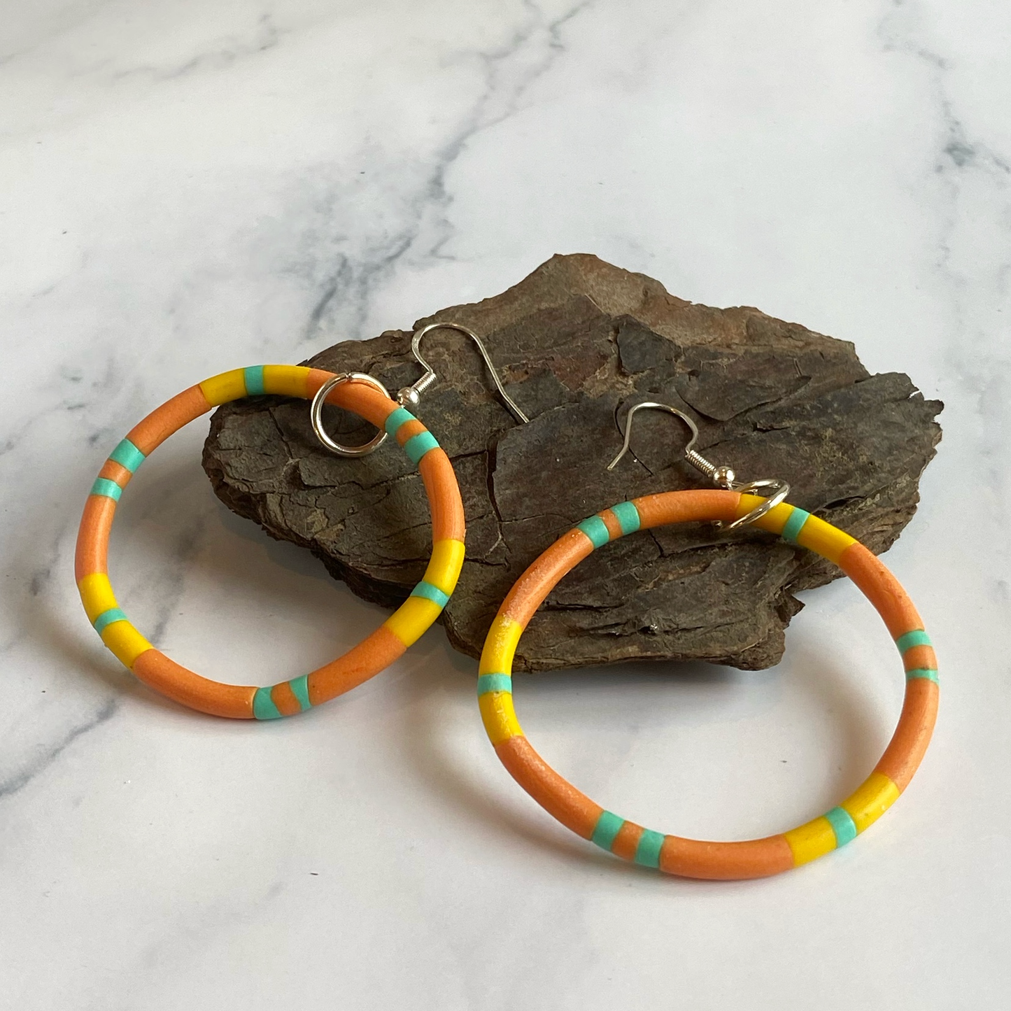 Colorful hoop earrings with a natural stone background on a marble surface