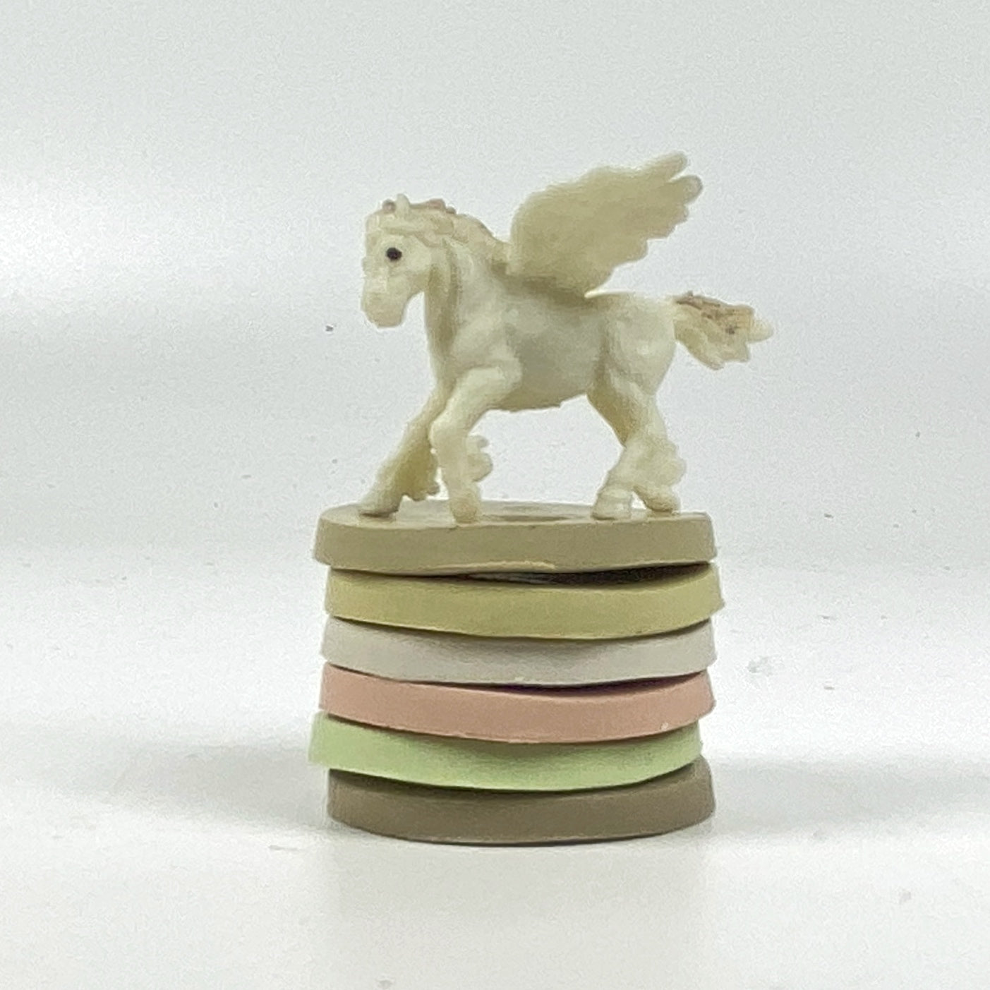 Sample clay discs in farmhouse palette colors, with a white pegasus for good luck