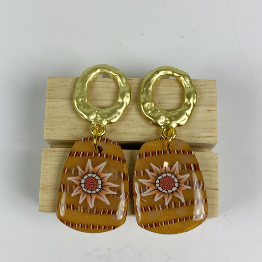 Saffron Daisy Polymer Clay Earrings  on a wooden block.
