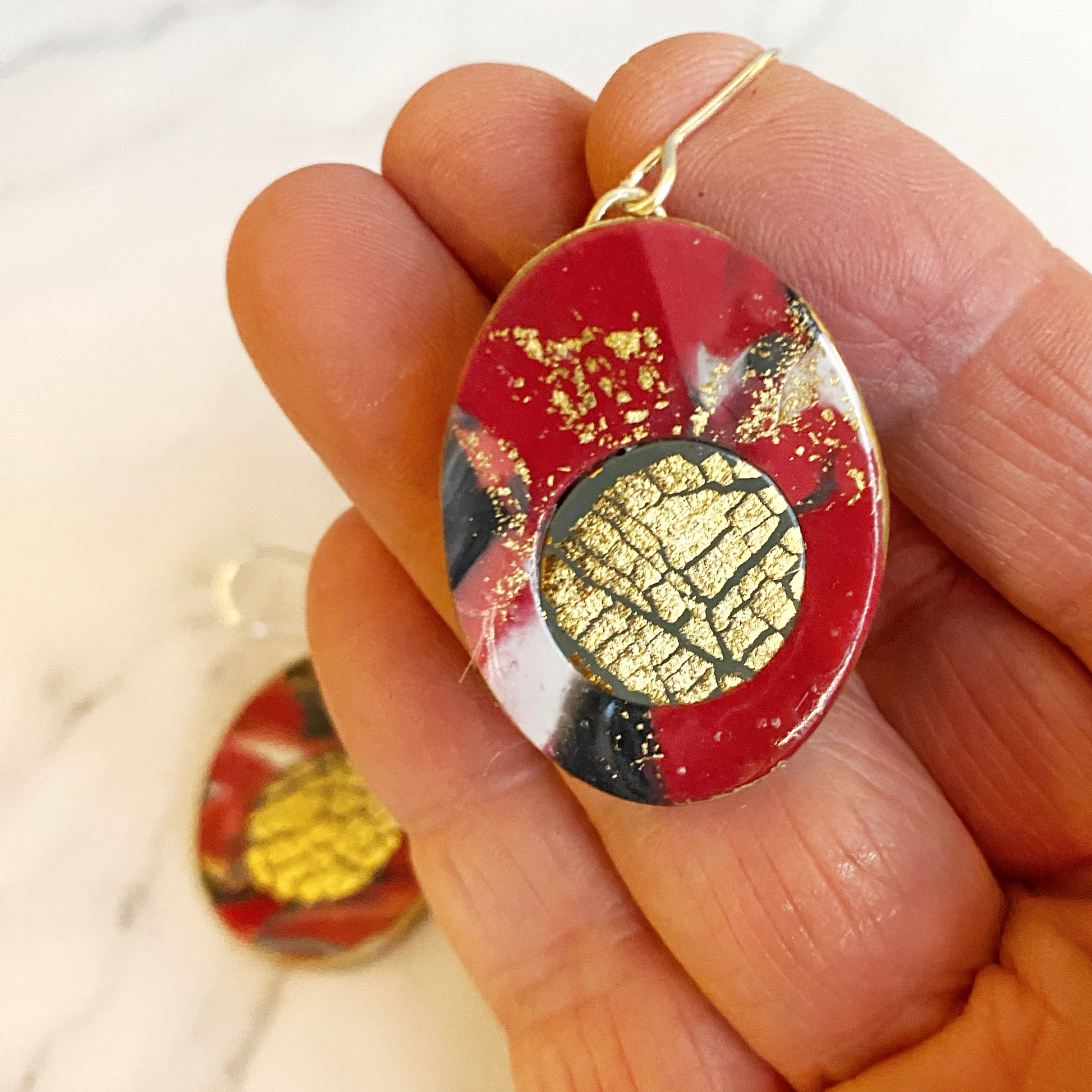Red Marbled Polymer Clay Earrings with Gold Inset handheld for size reference