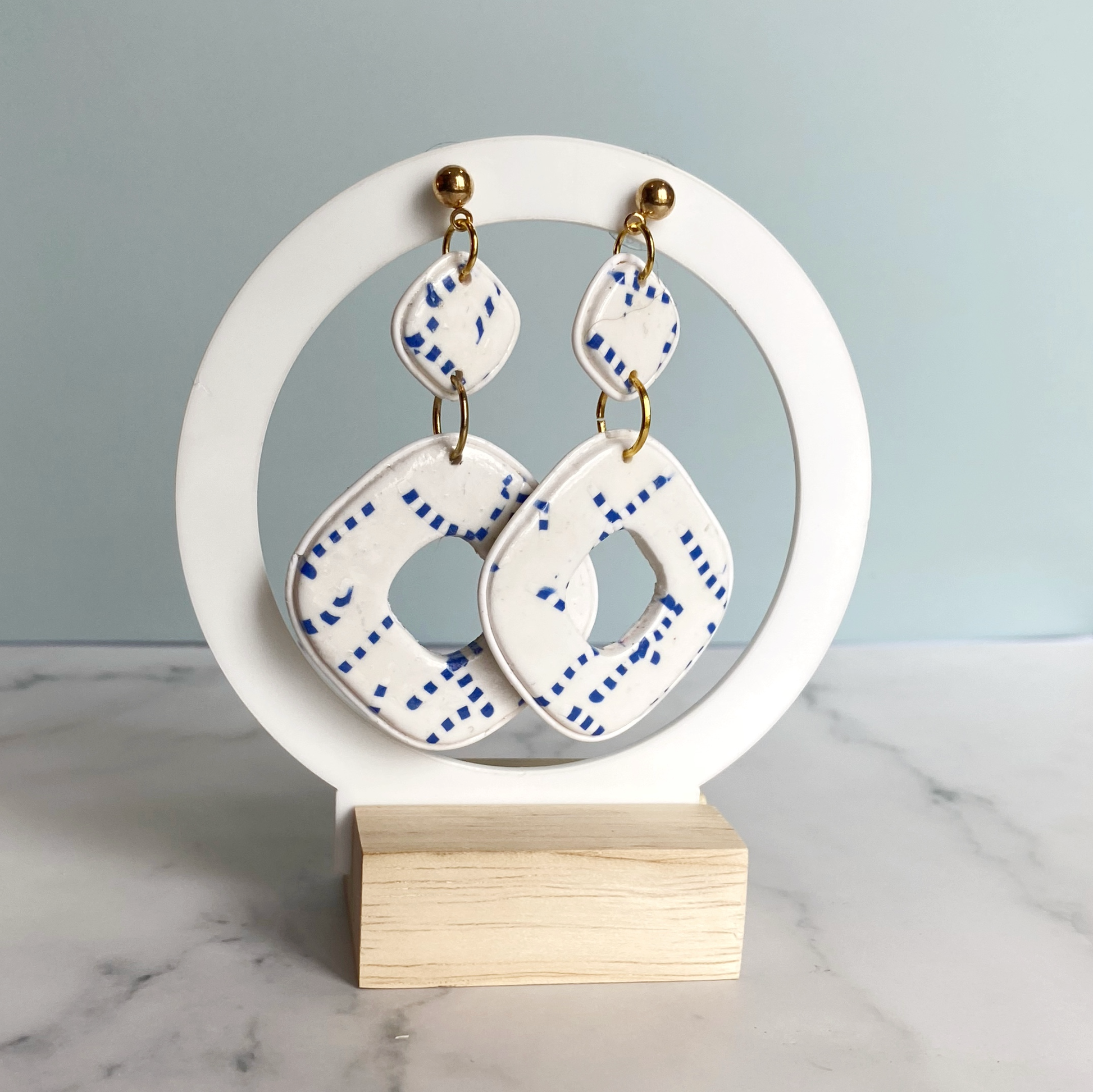 Blue and White Handmade Polymer Clay Square Dangle Earrings on a white display stand
