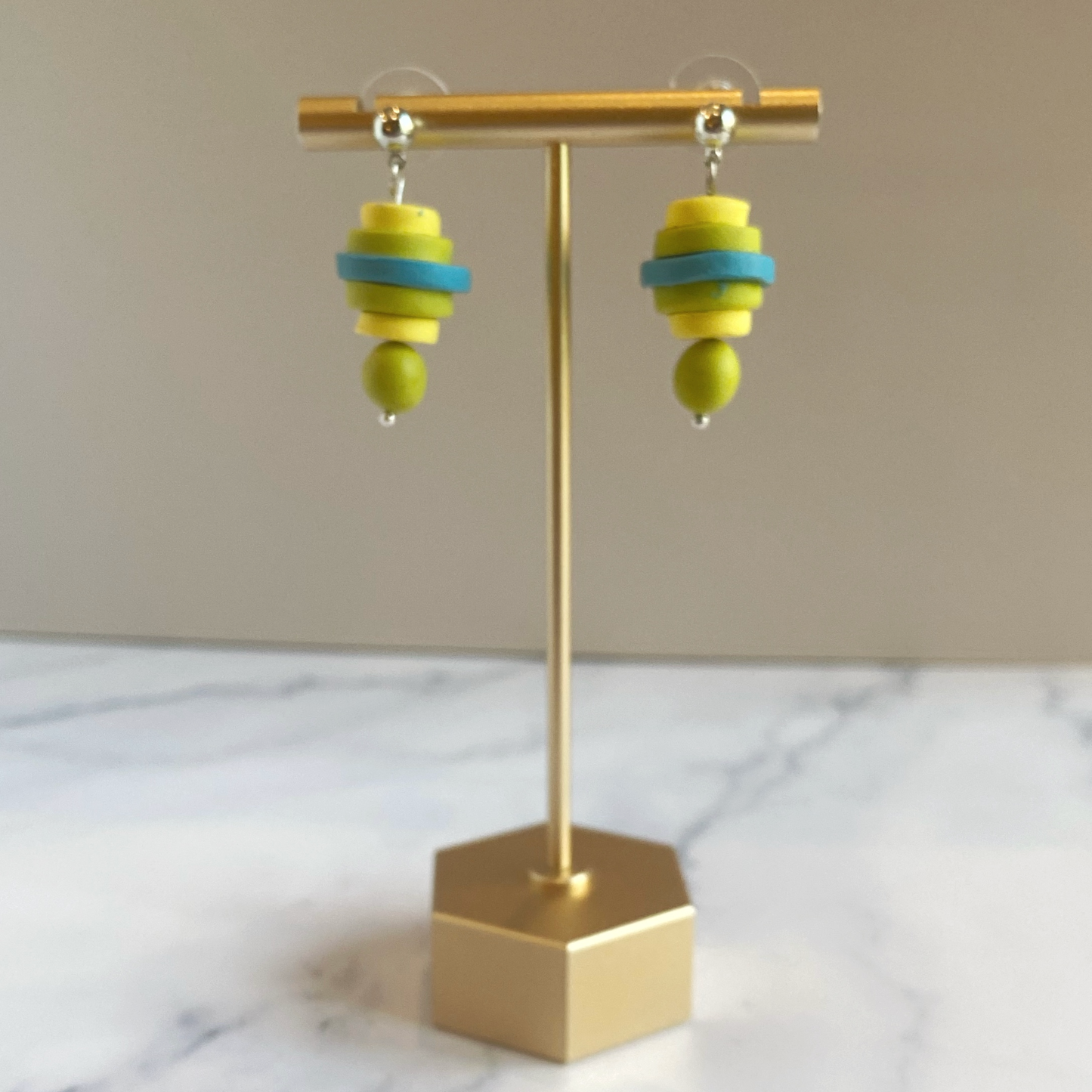 Colorful earrings on a gold earring stand with a beige background