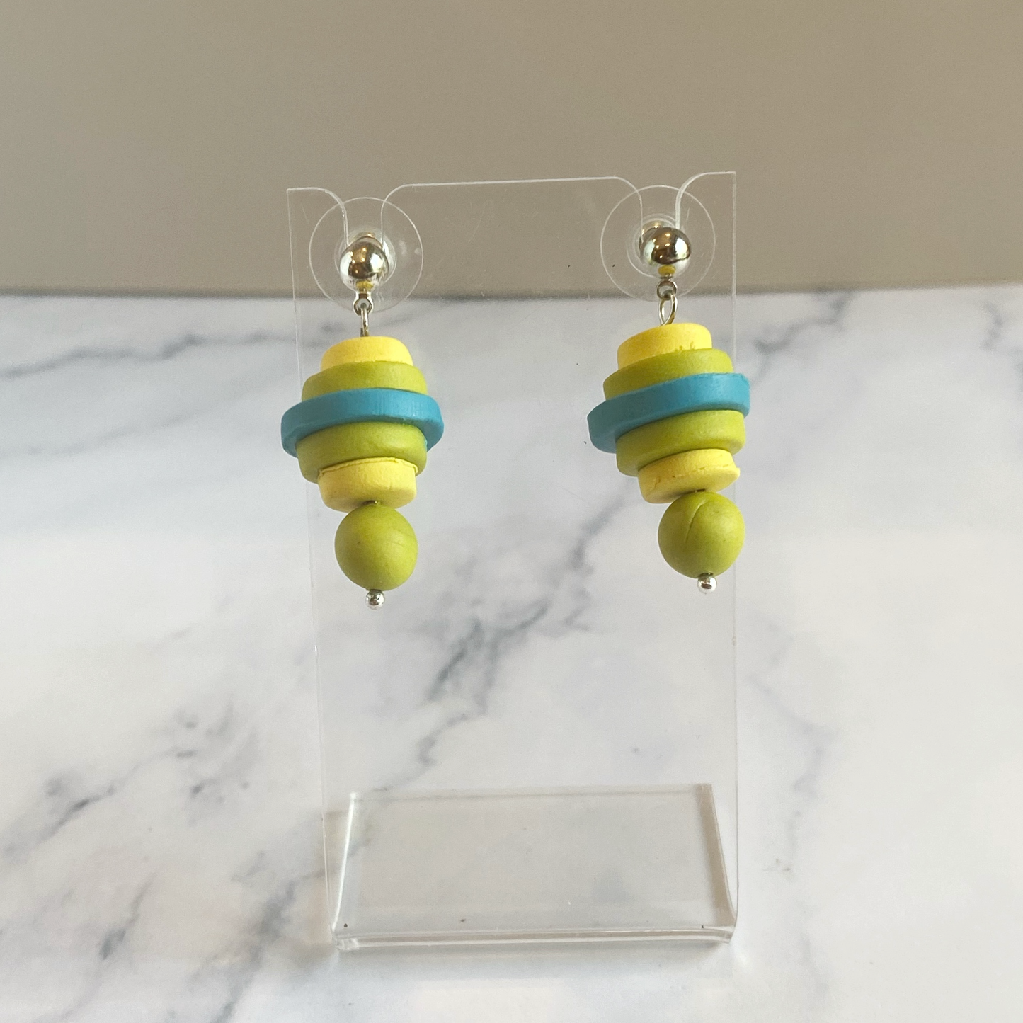 Earrings made of stacked discs of polymer clay displayed on an acrylic stand