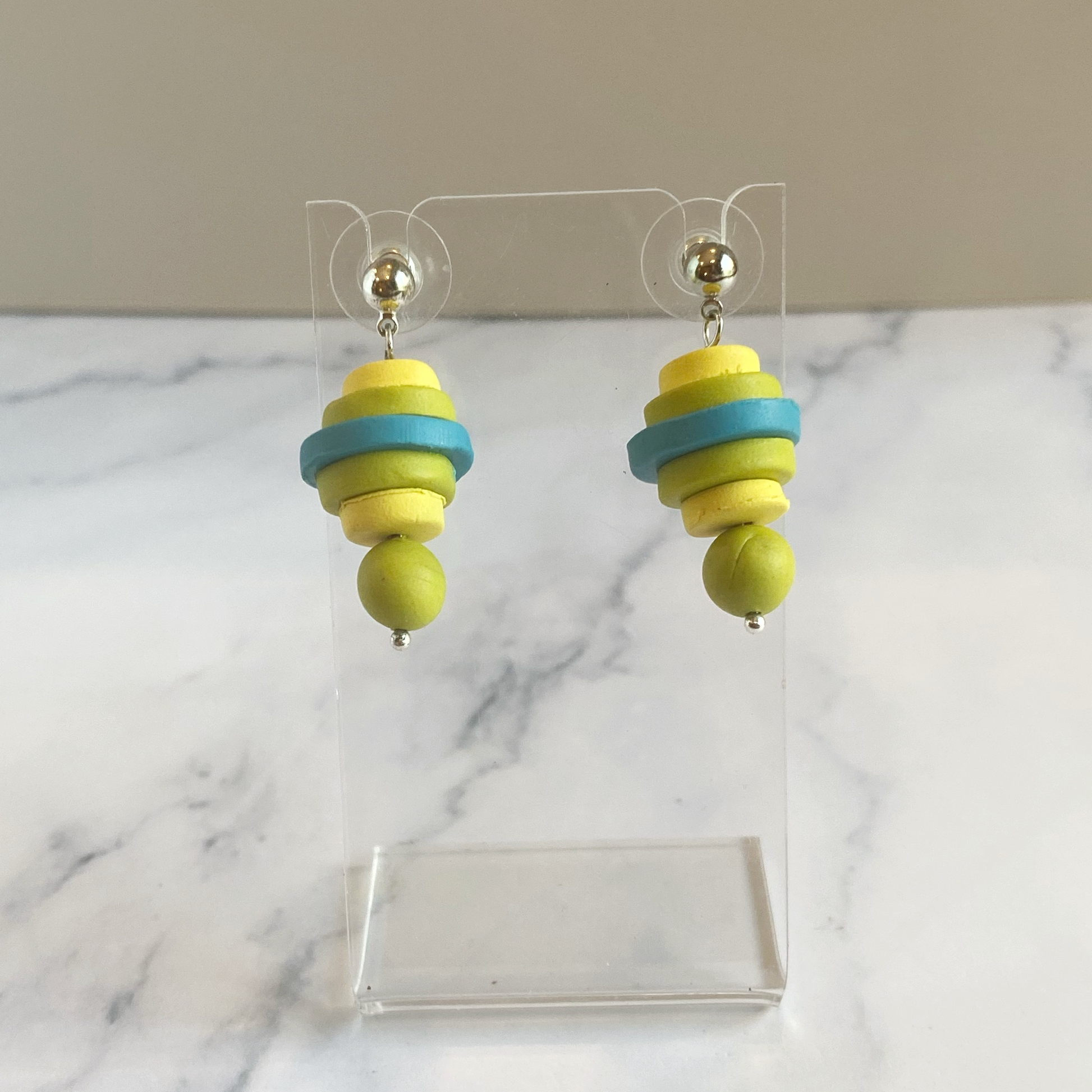 Earrings made of stacked discs of polymer clay displayed on an acrylic stand