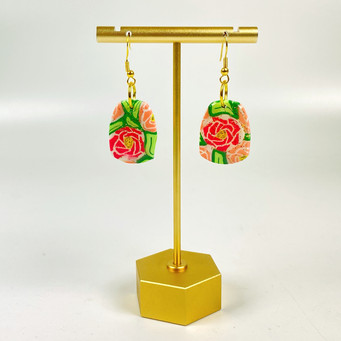 The Roses Handmade Polymer Clay Dangle Earrings on a brass earring display stand