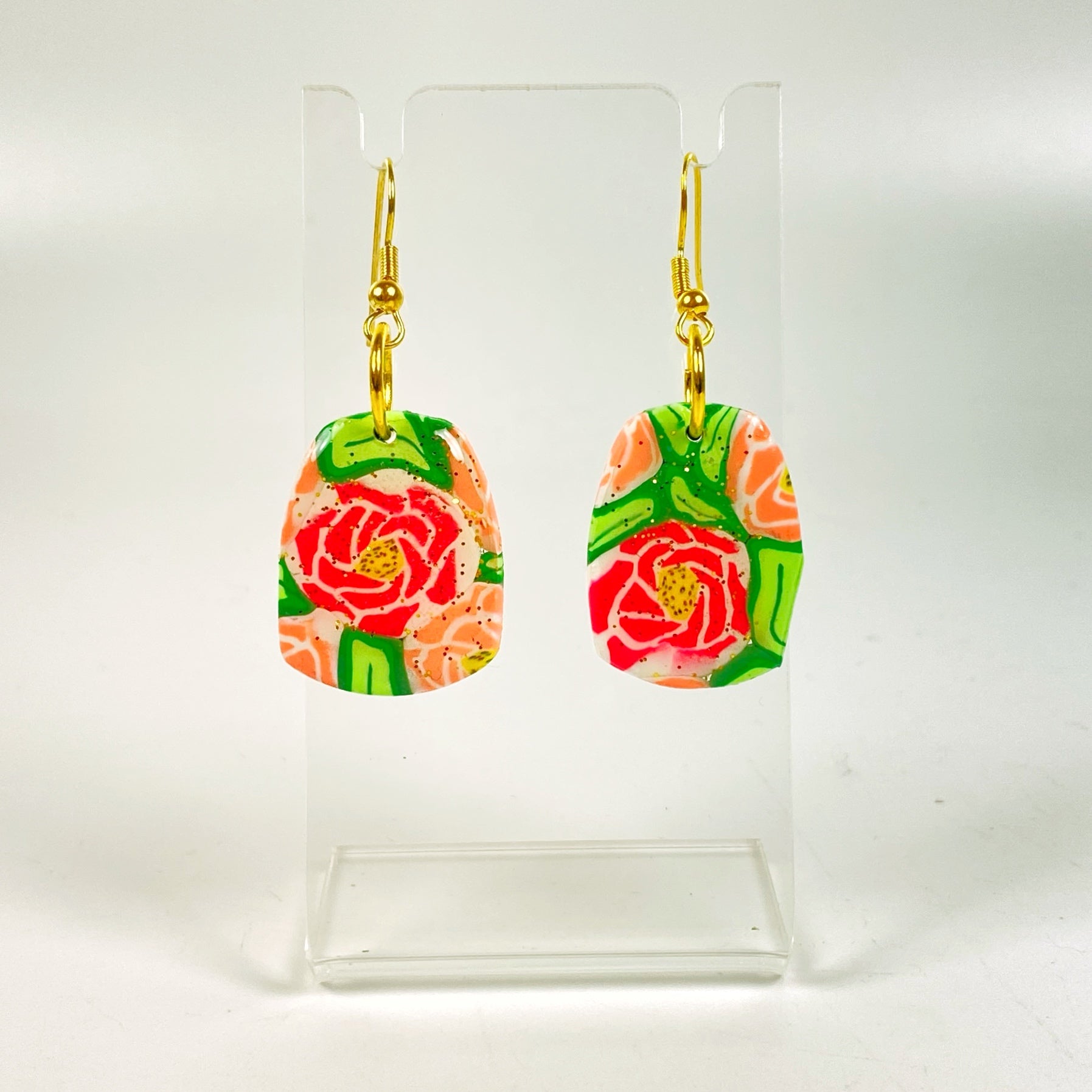 The Roses Handmade Polymer Clay Dangle Earrings on a small acrylic display stand