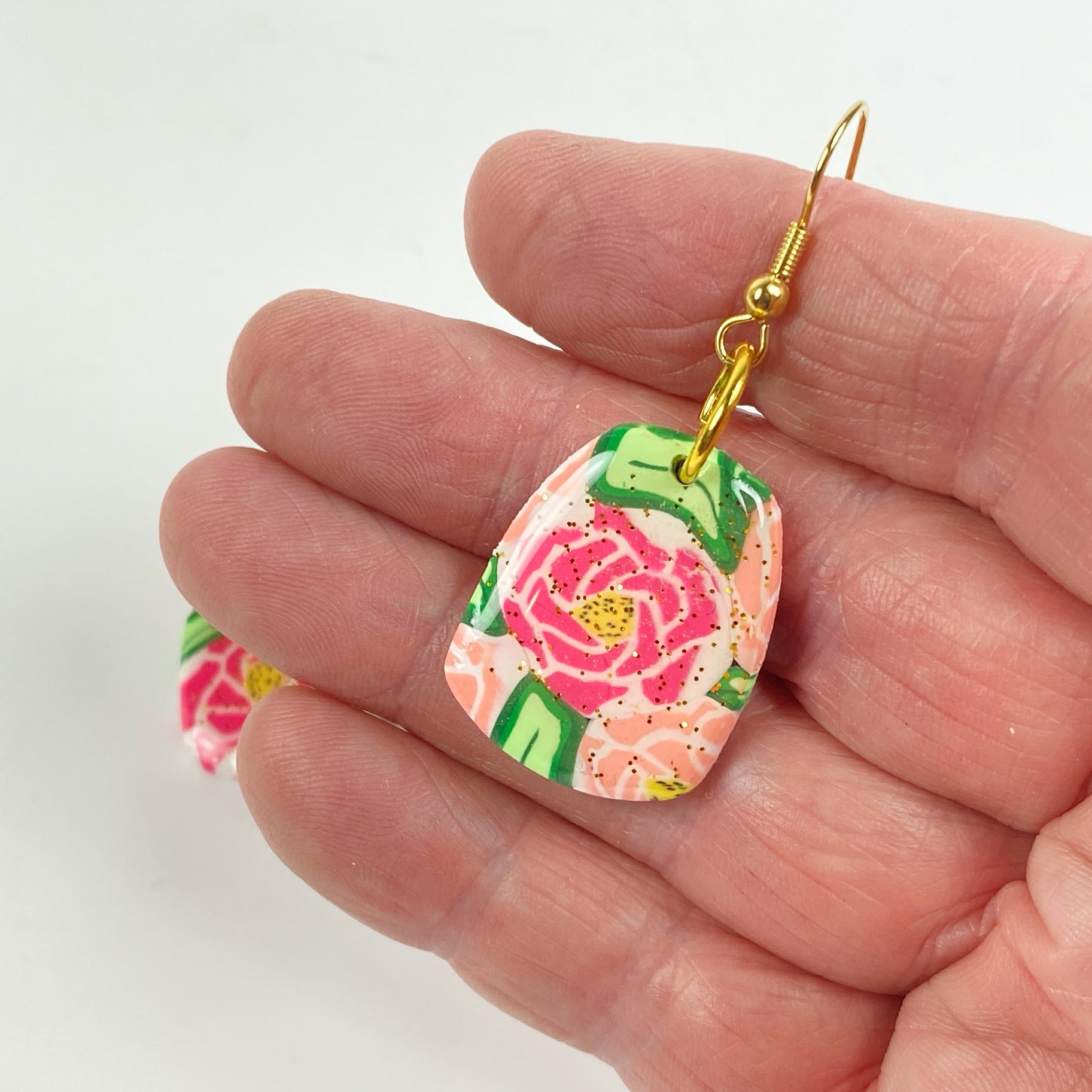 The Roses Handmade Polymer Clay Dangle Earrings handheld for size reference
