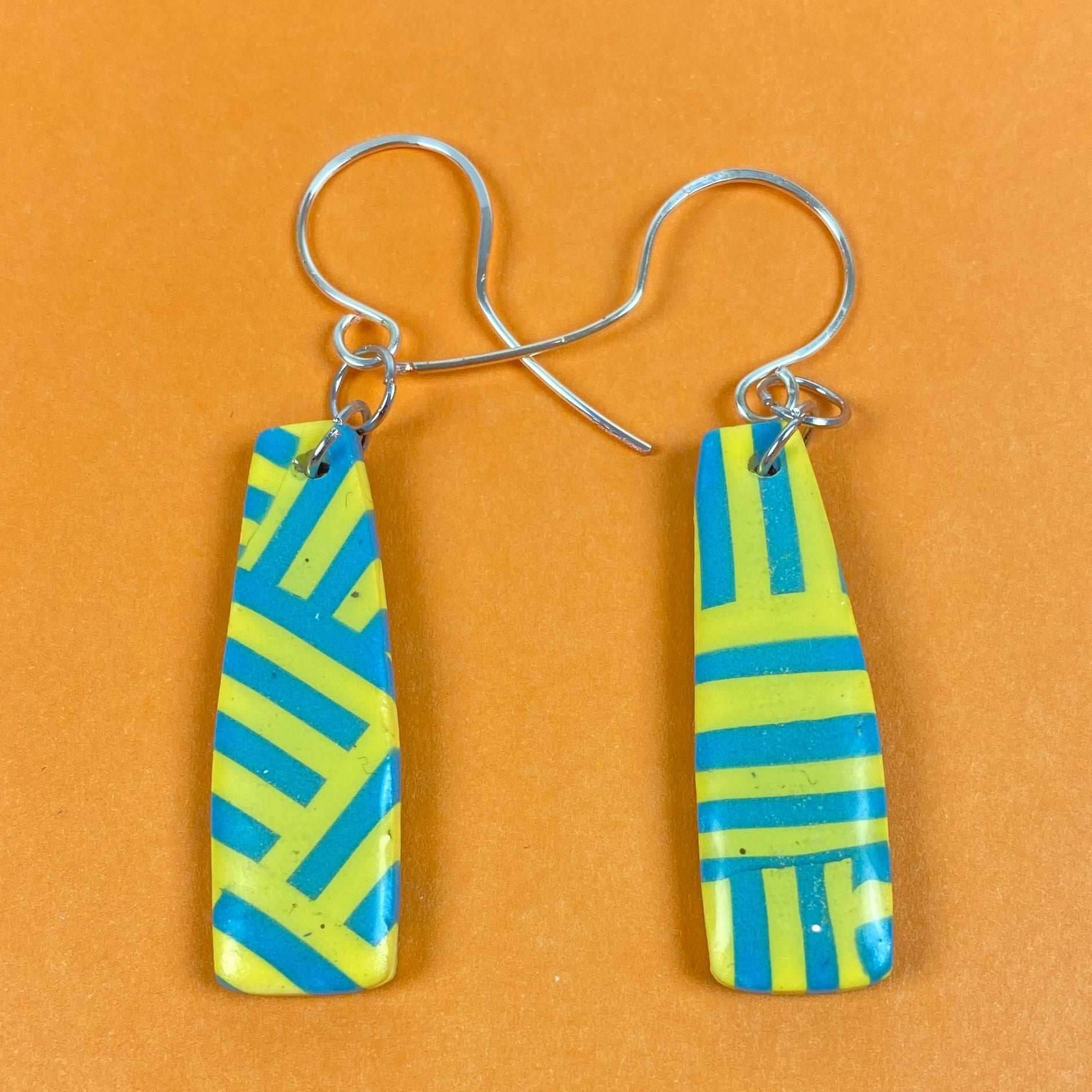 Turquoise & Yellow Braid Handmade Polymer Clay Dangle Earrings front view on an orange background