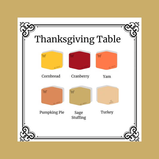 Thanksgiving table setting with colored cubes labeled Cornbread, Cranberry, Yam, Pumpkin Pie, Sage Stuffing, and Turkey on a gold background.