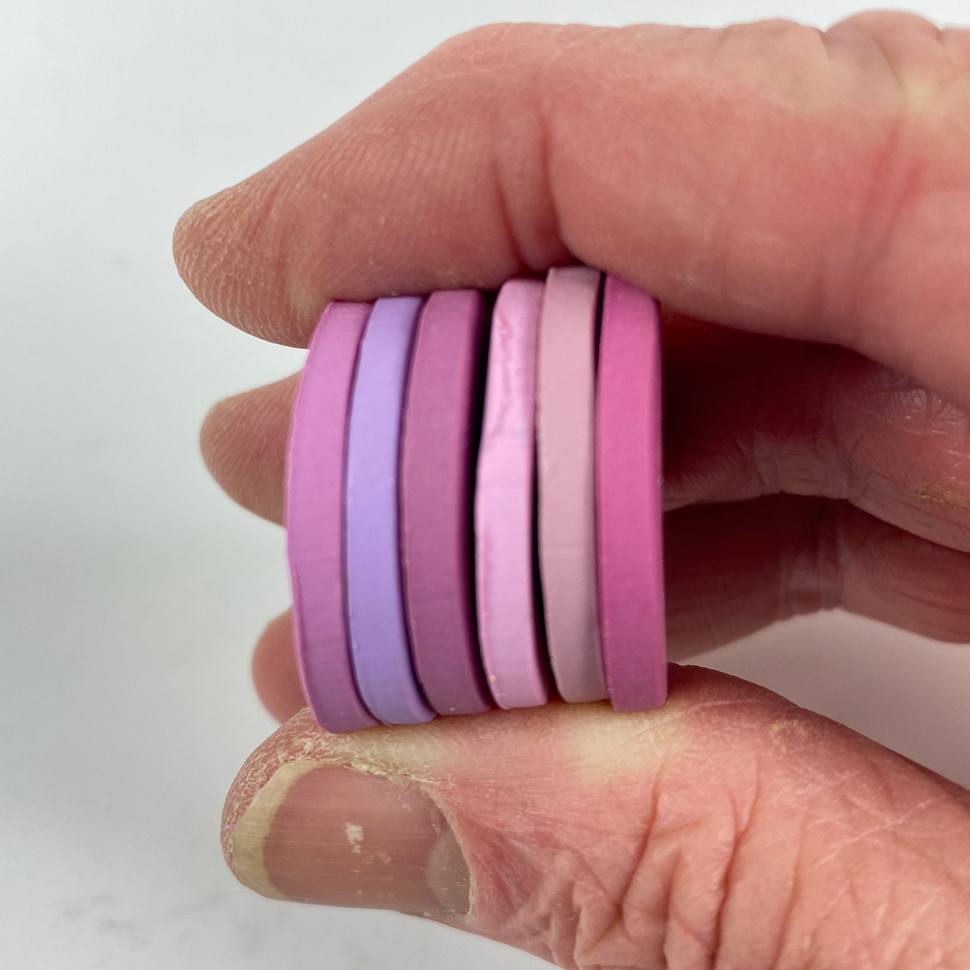 Polymer Clay Cupid’s Arrow Color Palette. Stacked sample discs of each clay color, held in a hand for a side view.