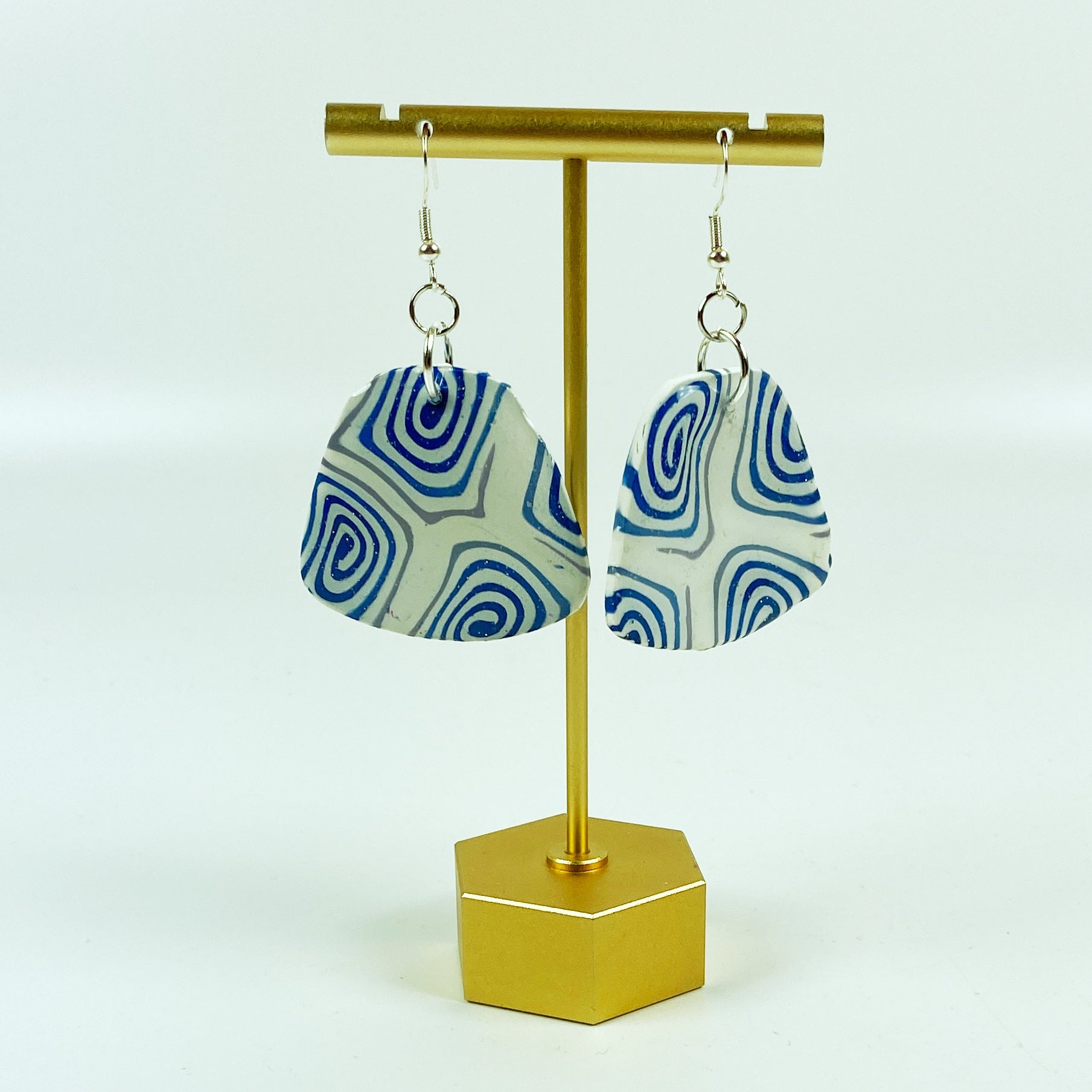 Swirling Cosmos Blue Polymer Clay Handmade Dangle Earrings on brass display stand