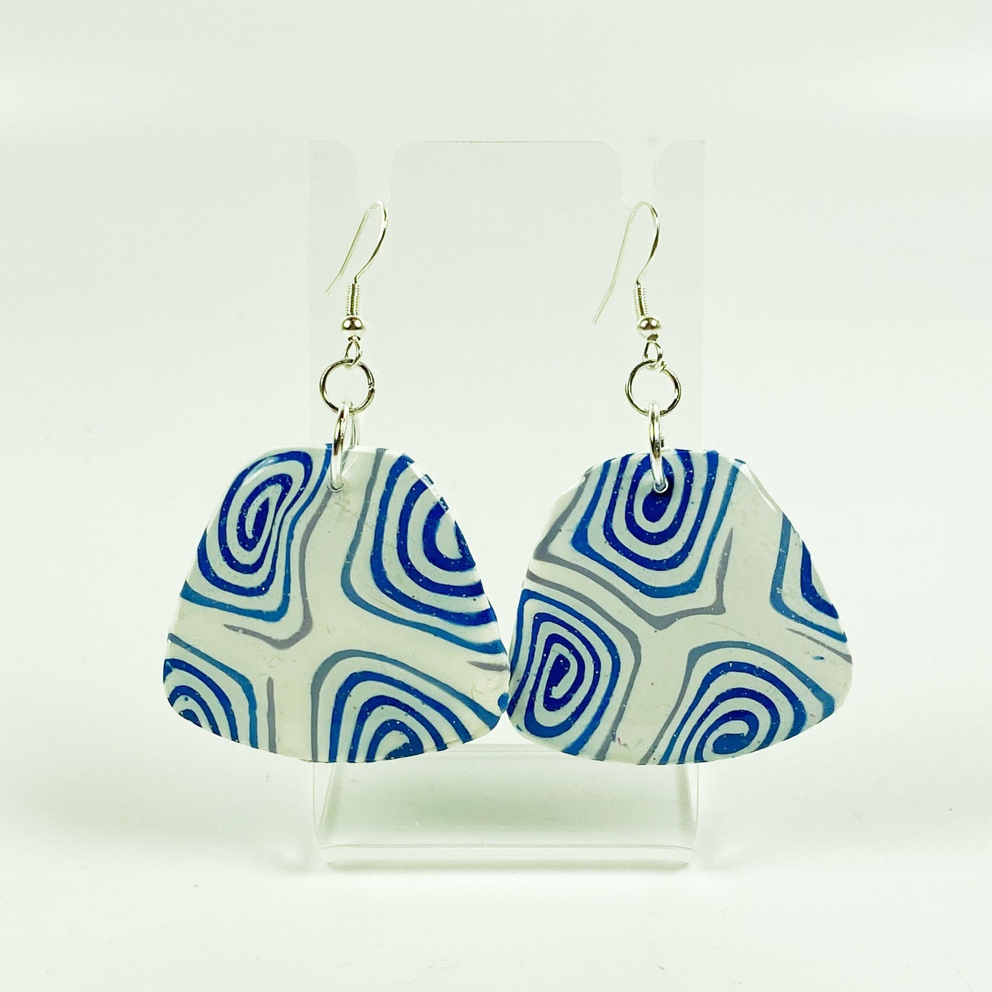 Swirling Cosmos Blue Polymer Clay Handmade Dangle Earrings on small acrylic display stand
