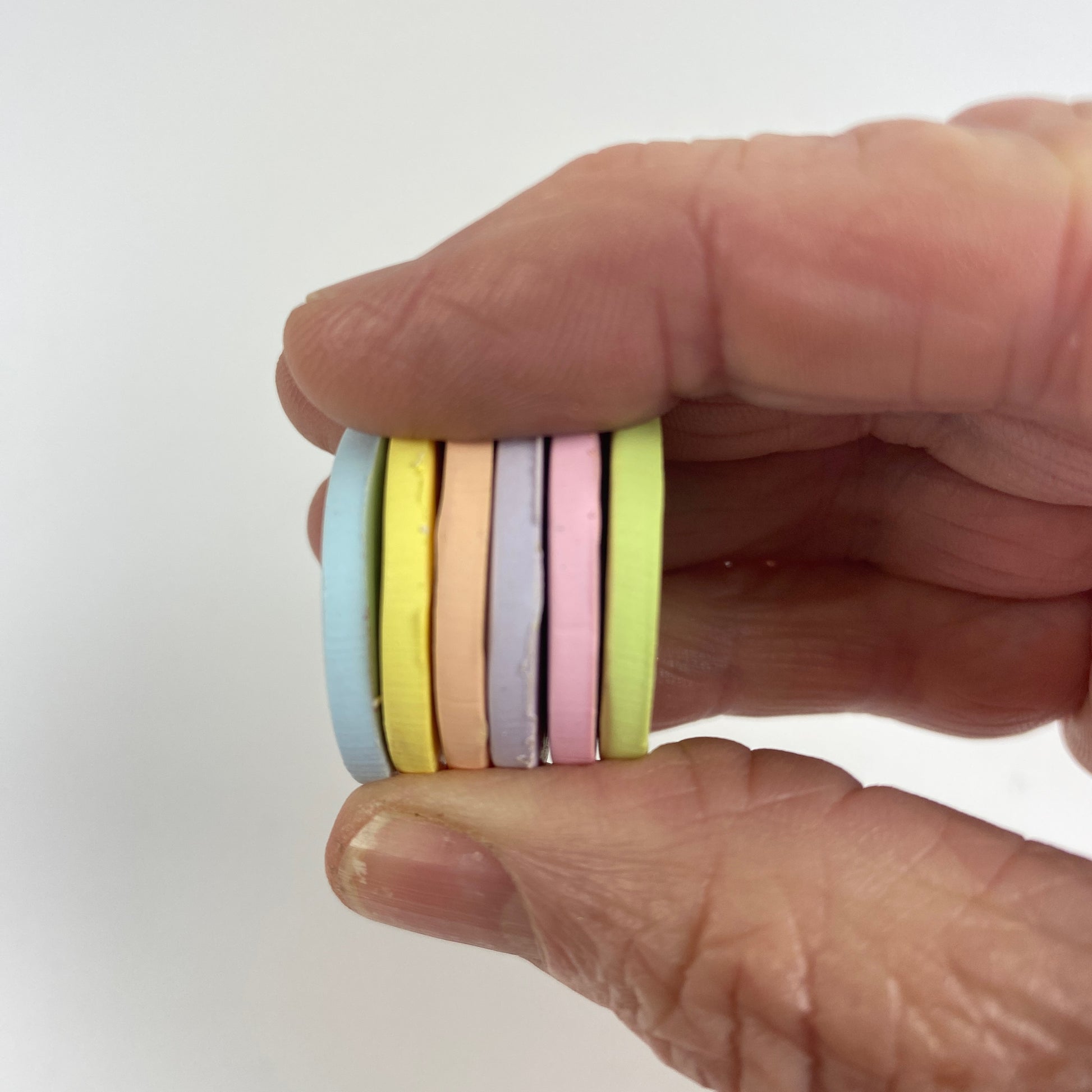 eaceful Easter Polymer Clay Secret Admirer Color Palette. Stacked sample discs of each clay color, held in a hand for a side view.